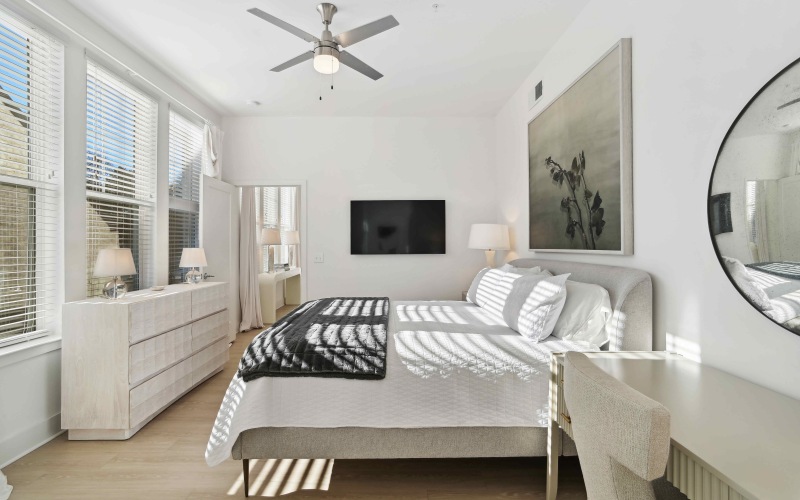 Oversized windows in primary bedroom with ceiling fan and light fixture