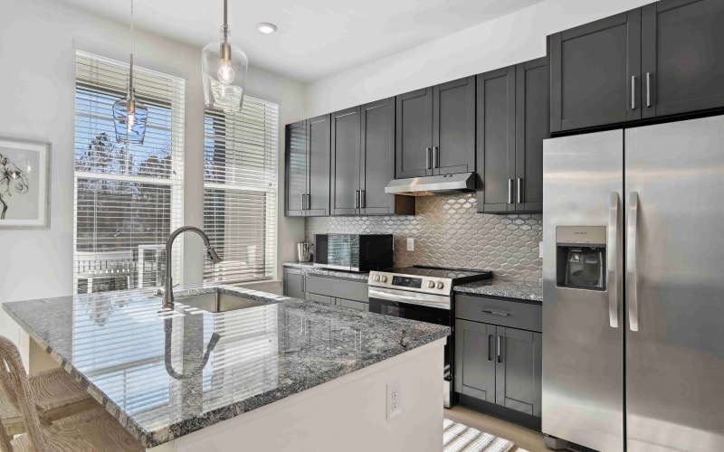 Guest suite kitchen with stainless steel appliances, dark cabinets, and large island